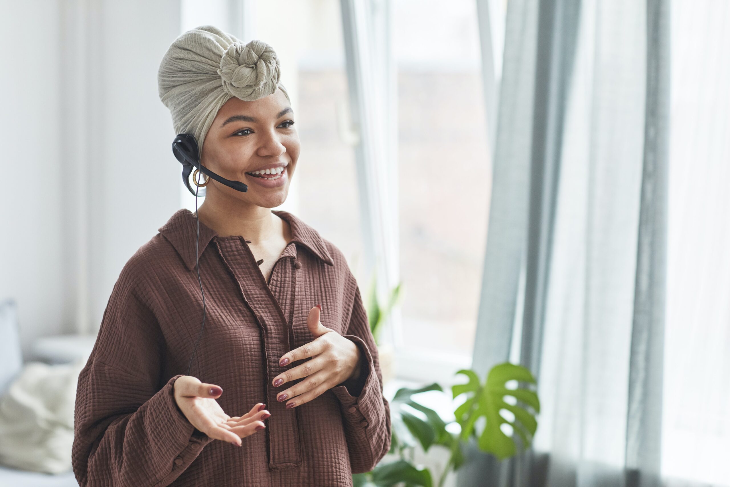 A lady in a brown shirt wearing a headset and in conversation: outsourced customer service