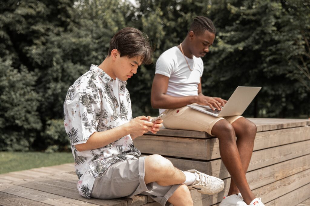 Young men browsing a laptop and smartphone: outsourced social media
