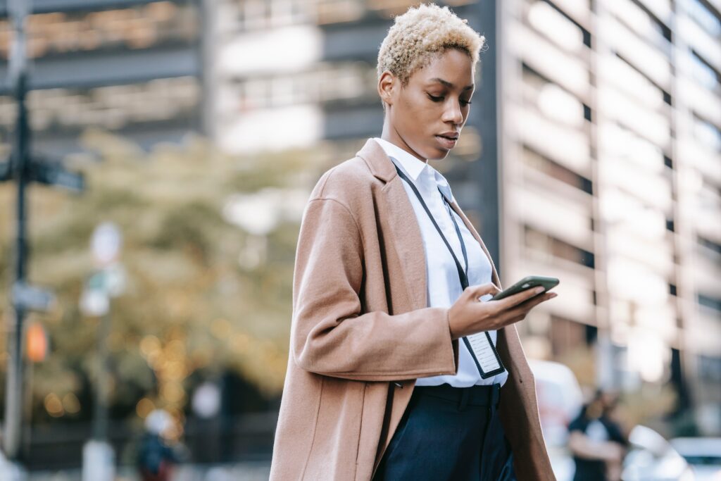 A businesswoman browsing a phone on the street: outsourced sales representative
