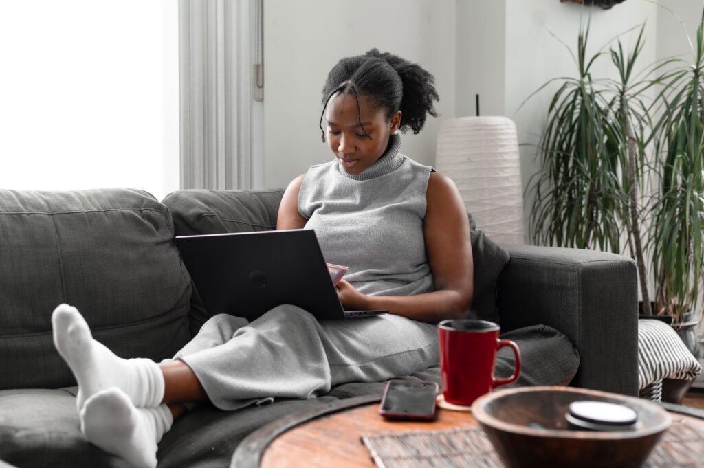 A woman using a laptop while sitting on a couch: outsourced compliance