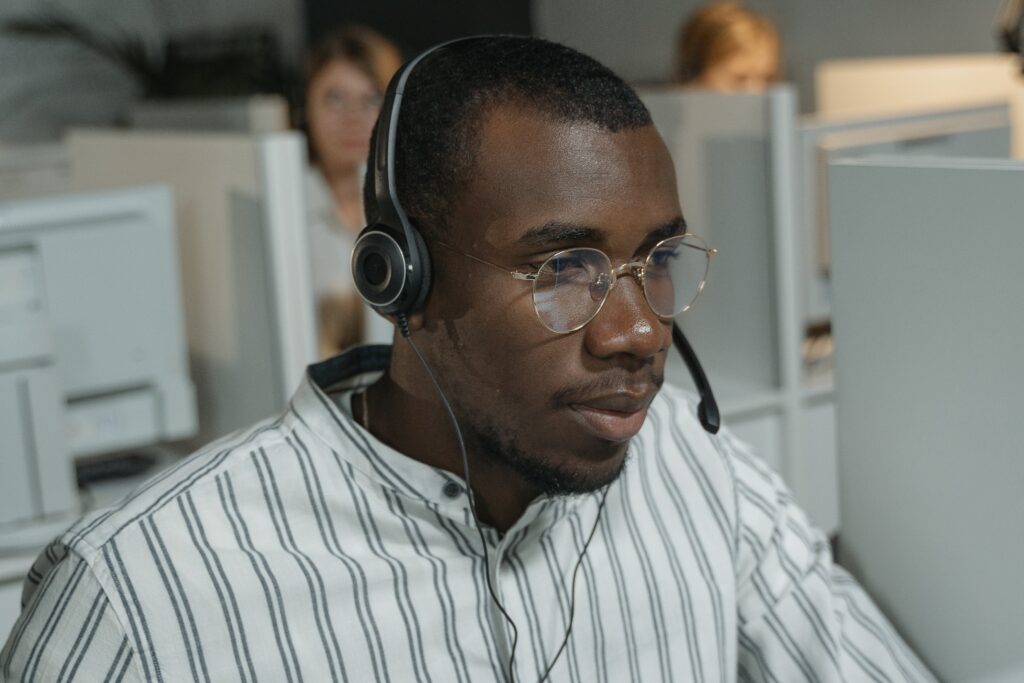 A man in a striped button up shirt wearing black headphones: outsourced live chat
